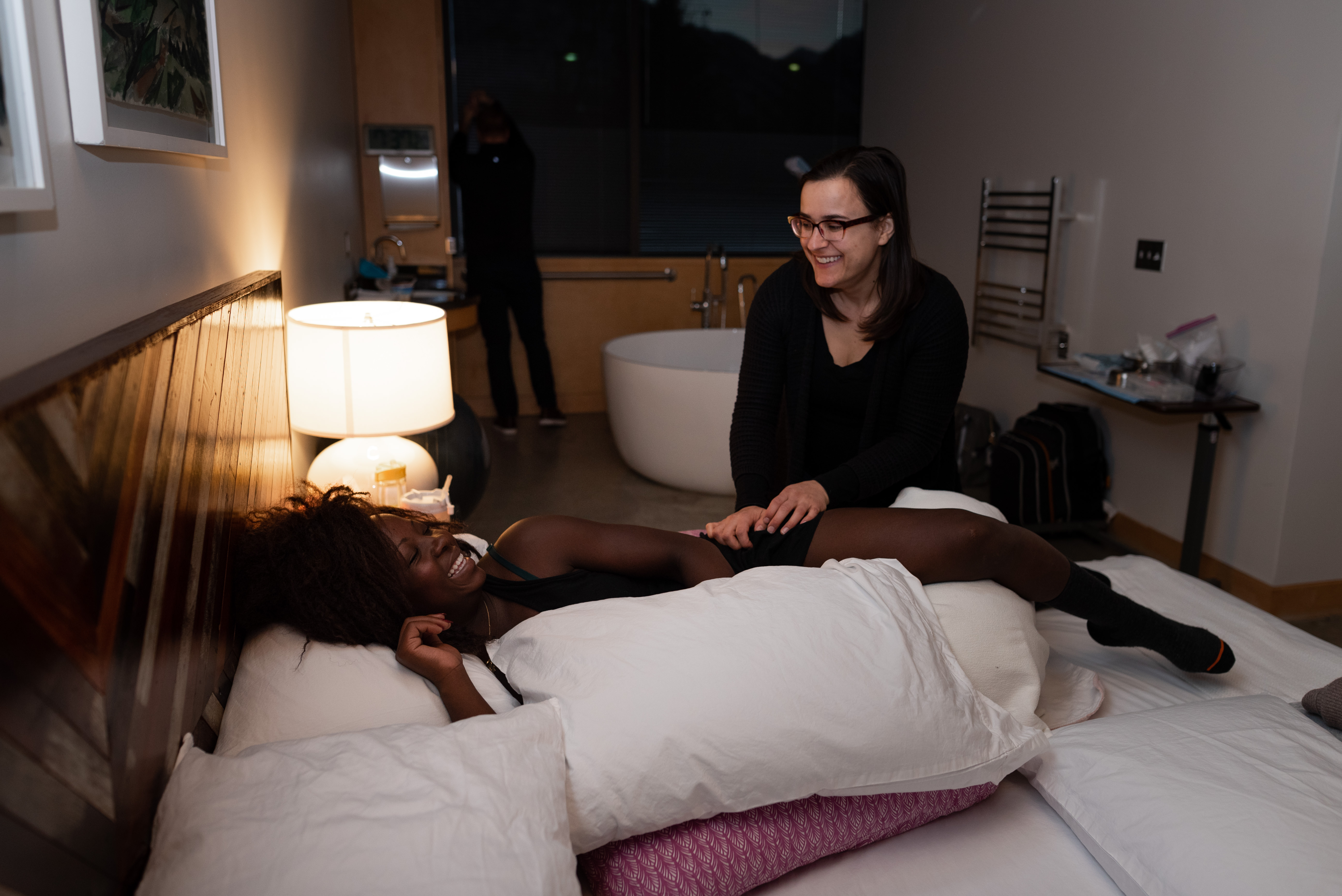 Utah doula smiles at laboring mother while she massages her legs