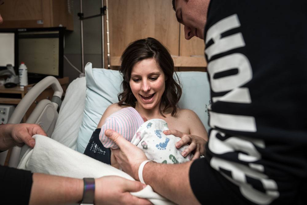 Mom smiles as she is handed her newborn baby