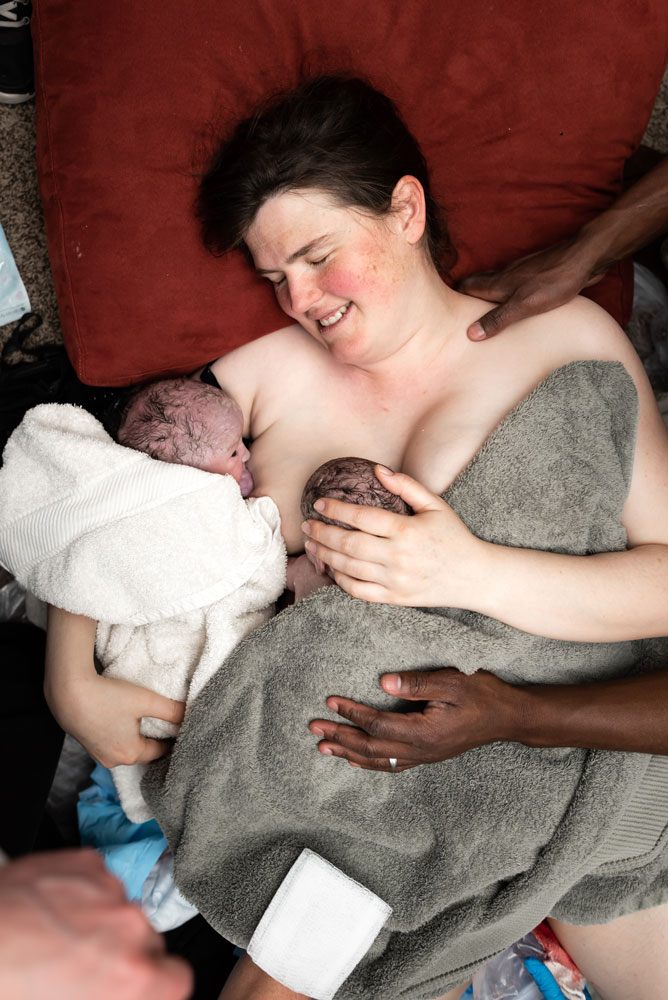Mom looks at her newborn sons and smiles after a Utah home birth