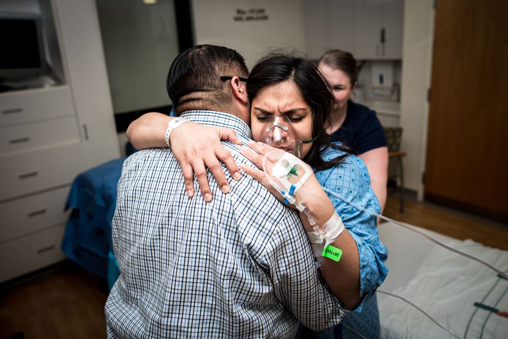 Laboring mother hugs onto dad while experiencing contractions during a birth story session