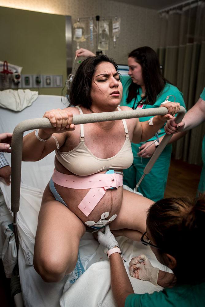 Laboring mother using squat bar while pushing in labor