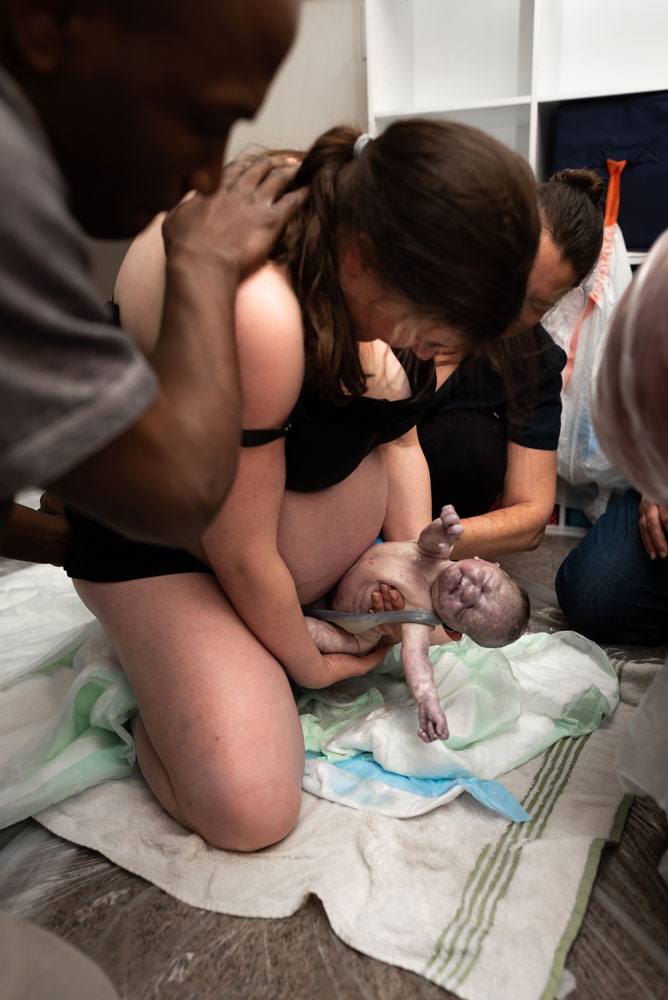 Twin A is born into his mother’s hands with dad offering a supportive hand
