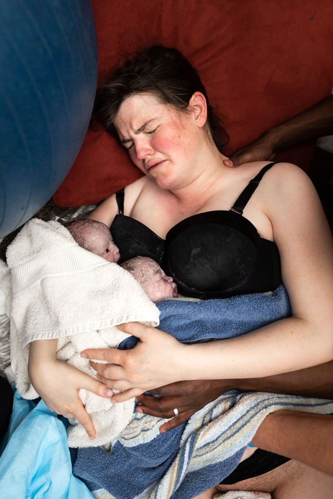 Mom holds twins while dad offers support after a home twin birth