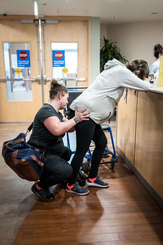 Doula applies counter pressure to moms hips in the hosptial hallway