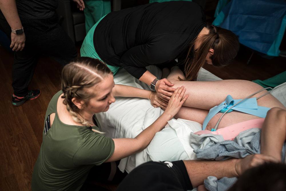 Doula and midwife applies counter pressure on mothers knees during contractions