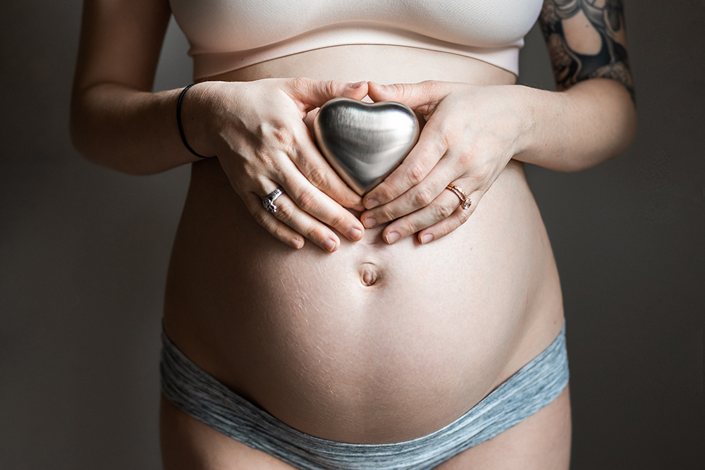 Mother holds urn of baby who passed away over her pregnant belly