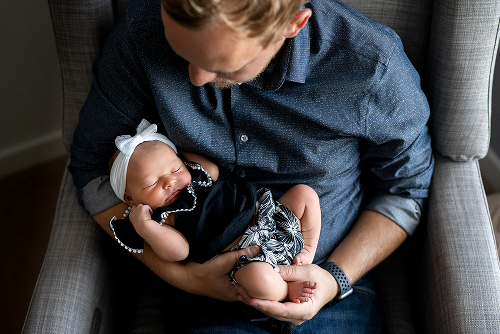 Newborn baby girl sleeps in dads arms