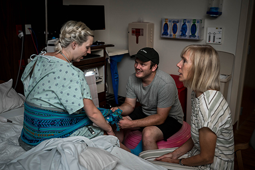 Laboring woman, mom and husband sit in hospital room during labor
