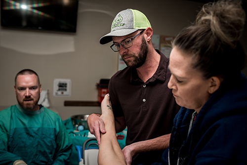Dad holds a leg while mom pushes during birth of son