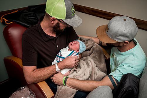 New dads admire their newborn son in hospital chairs