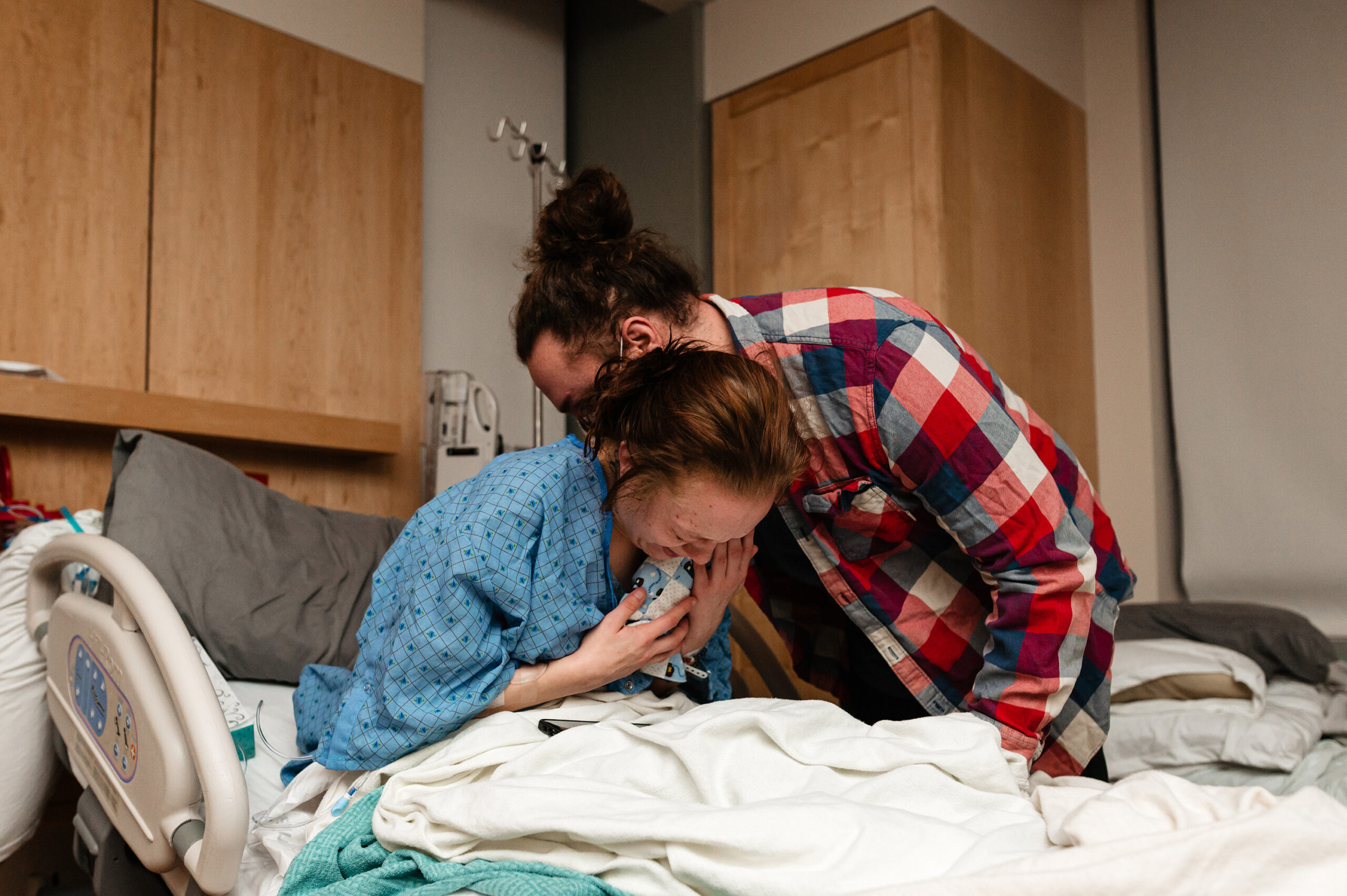 Mother and father hold baby and cry after the loss of their son during pregnancy