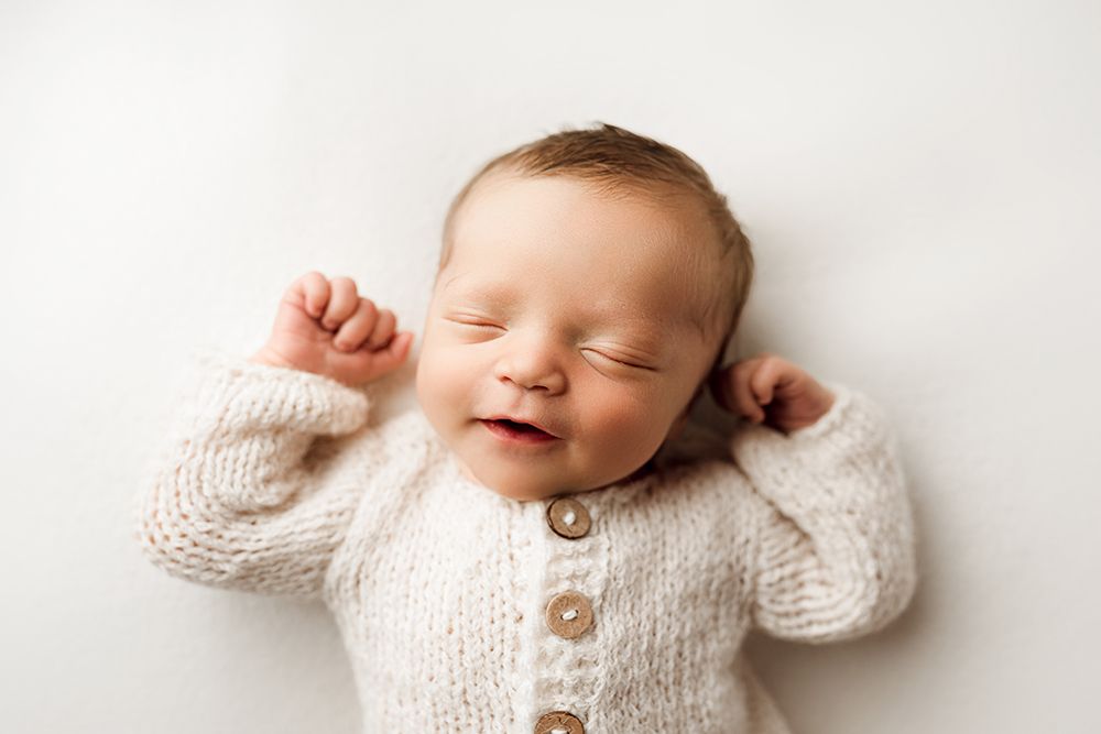 Newborn baby smiles in his sleep during his newborn photography session